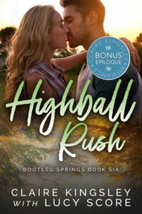 The bonus epilogue book cover for Highball Rush, a novel by Claire Kingsley with Lucy Score, is an image of a blonde woman leaning in to kiss a dark haired man while the sun sets in the background, she has one arm wrapped around his shoulders.