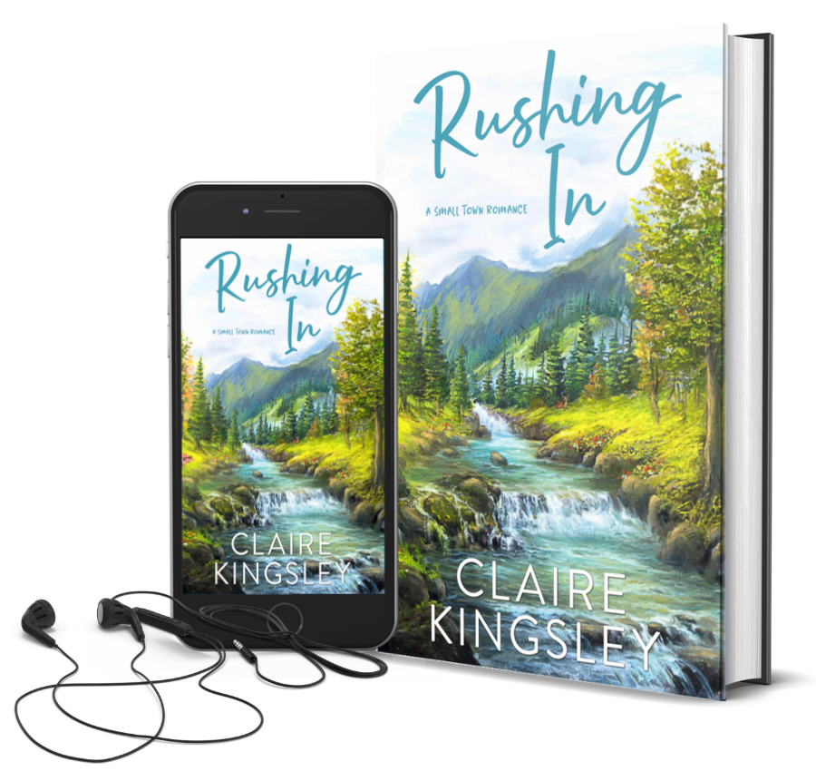 The book cover for Rushing In, a small-town romance by Claire Kingsley, is an illustrated image of a fast flowing river deep in the woods with tall trees, flowers and rocks lining its bank. In the distance is a beautiful green mountain range and pine trees. Next to the book is a phone showing the cover with a pair of wired earbuds.