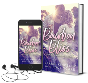 The book cover for Bourbon Bliss, a novel by Claire Kingsley with Lucy Score, is an image of a man and a woman dancing together in the sunset , his arm wrapped around her back while their hands are clasped tightly together. Next to the book is a phone showing the cover with a pair of wired earbuds.
