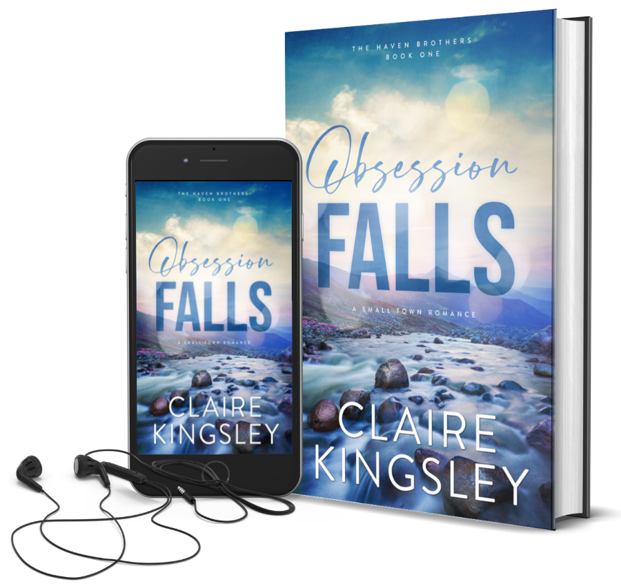 The book cover for Obsession Falls, a small-town romance by Claire Kingsley, is an image of a misty river at dawn flowing between two rocky hillsides with mountains in the distance. There are tones of blue, purple, and green. Next to the book is a phone showing the cover with a pair of wired earbuds.